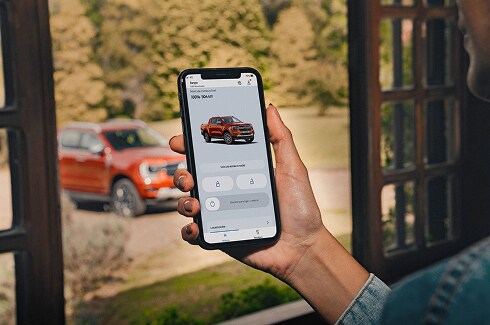 Celular mostrando o app FordPass Connect com o Ranger Raptor em segundo plano